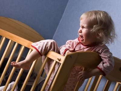 Photo d'un enfant qui pleure et qui refuse de dormir, qui veut sortir de son lit pour illustrer l'intérêt des consultations sommeil proposées par Amanda Tichit